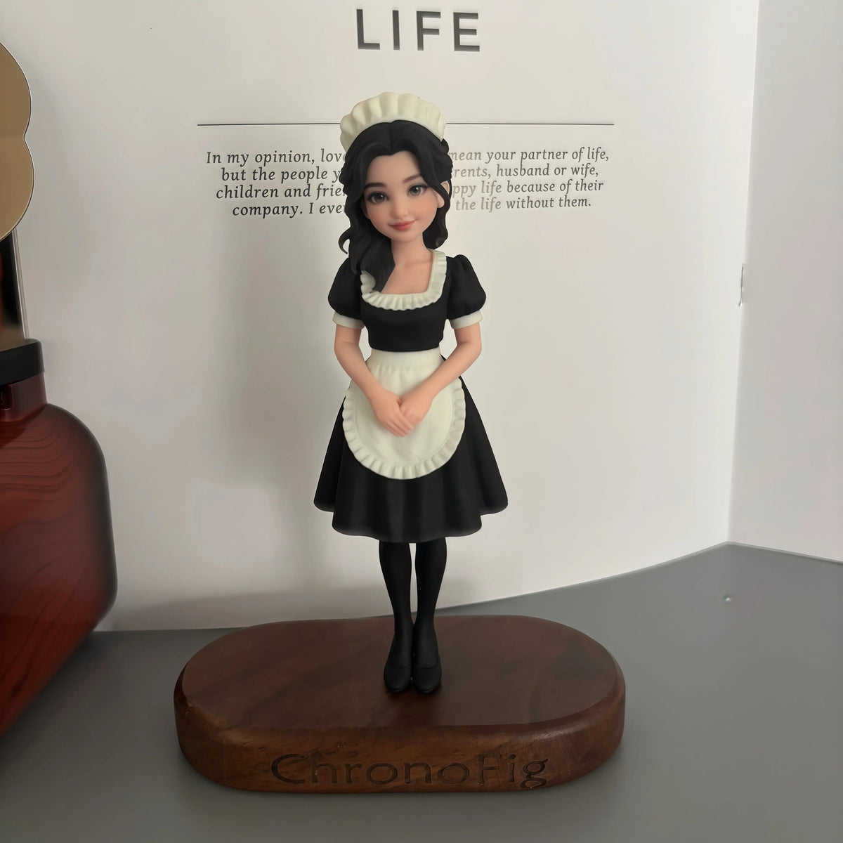 Real product photo of a personalized ChronoFig Maid 3D figurine created from a photo and displayed on a wooden base.