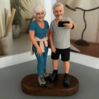Real product photo of a personalized ChronoFig Selfie-taking couple 3D figurine created from a photo and displayed on a wooden base.